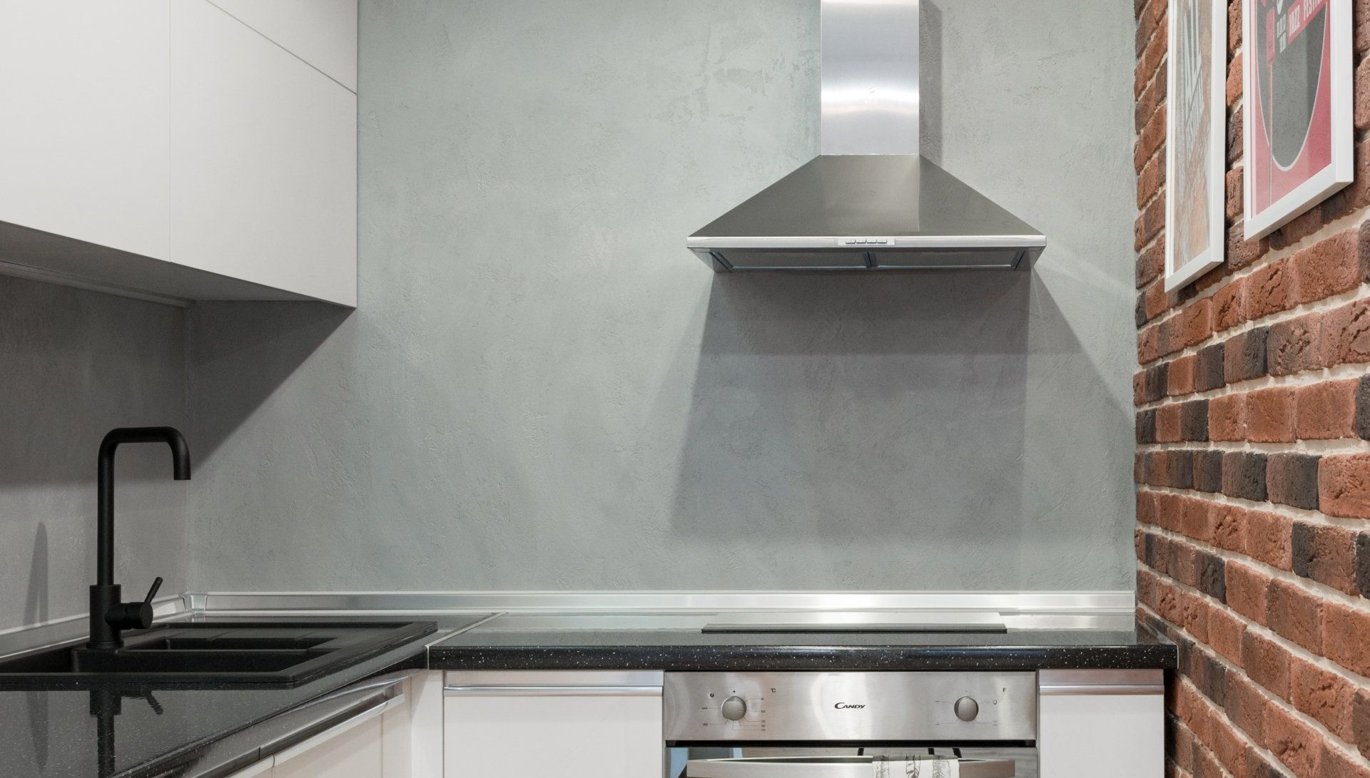 A kitchen with a stainless steel hood and a brick wall.