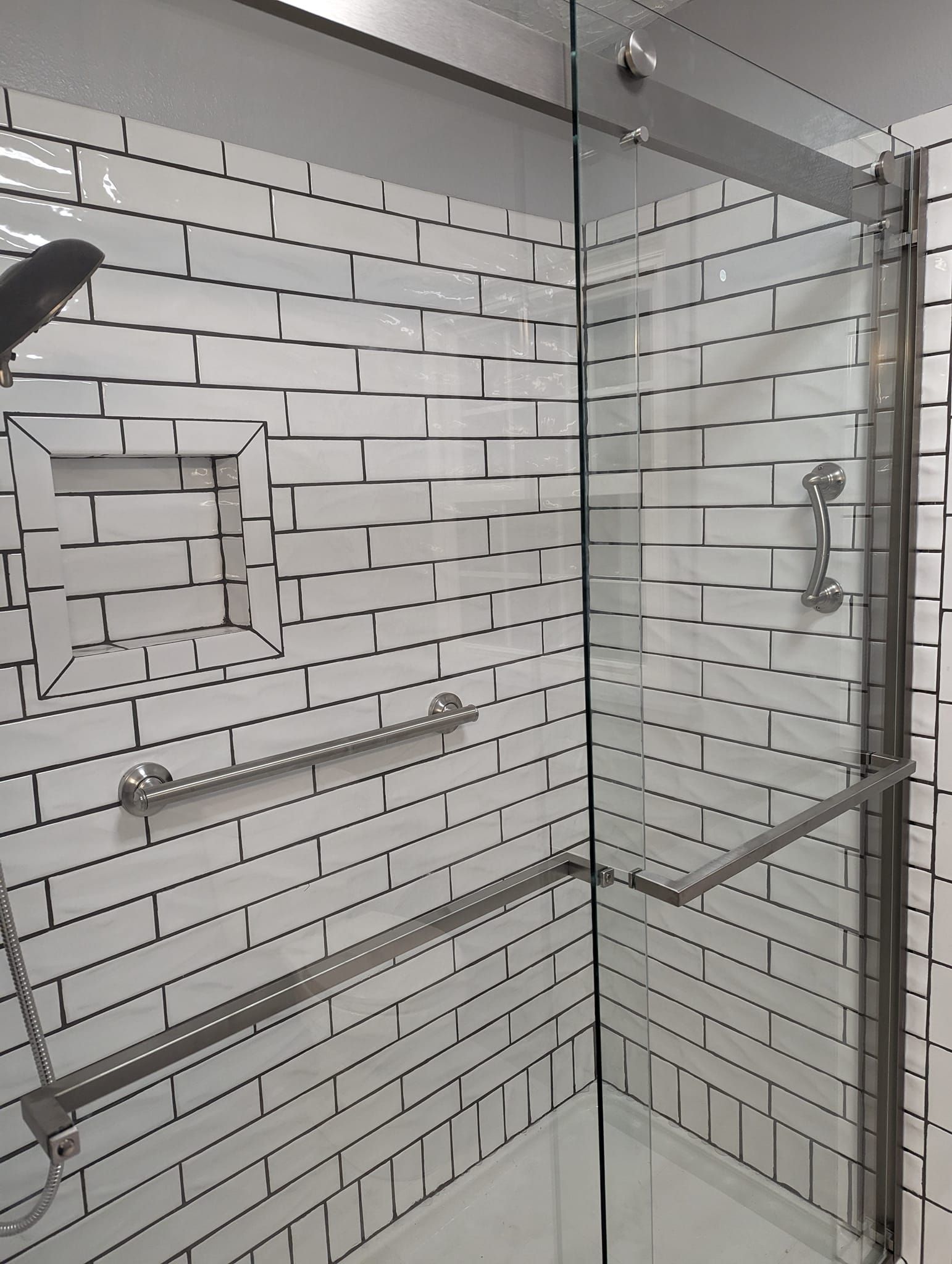 Shower with white subway tile, glass door, and silver fixtures.