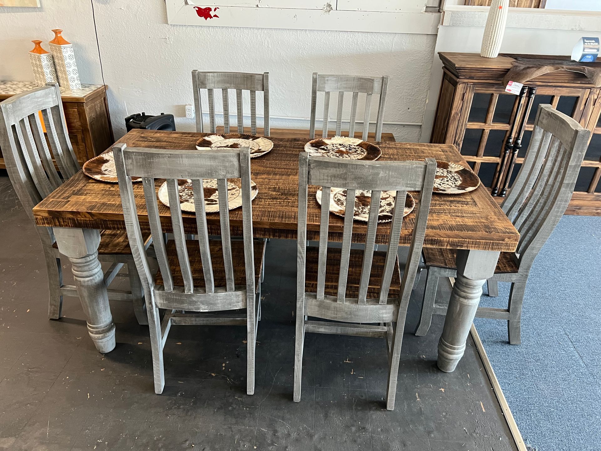 Rustic dining table set with chairs and bench in a showroom.