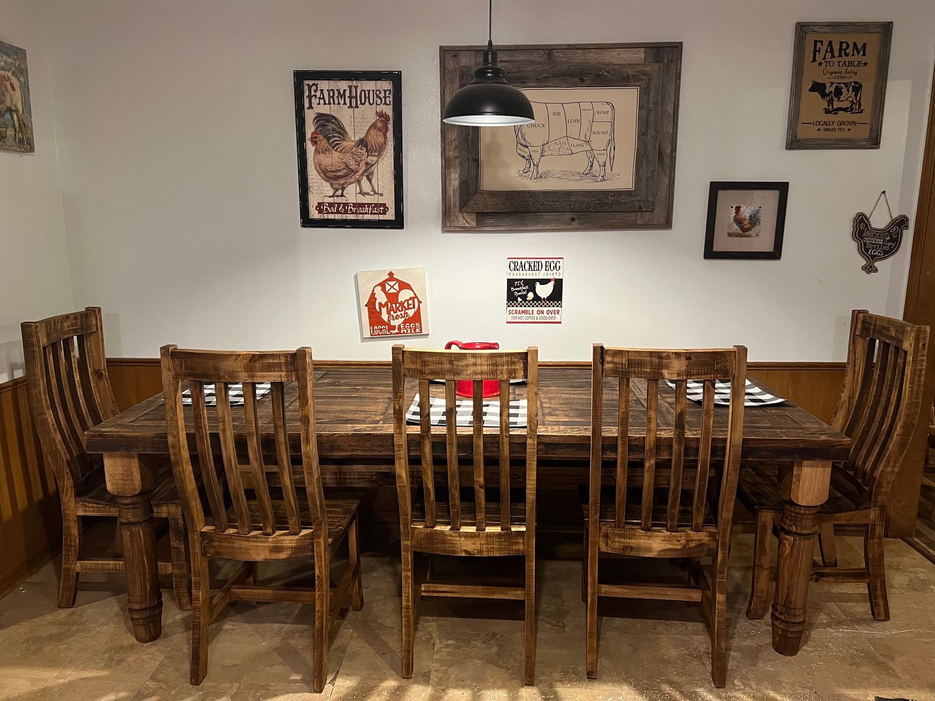 Rustic dining room with wooden table and chairs, chicken-themed art on the wall.