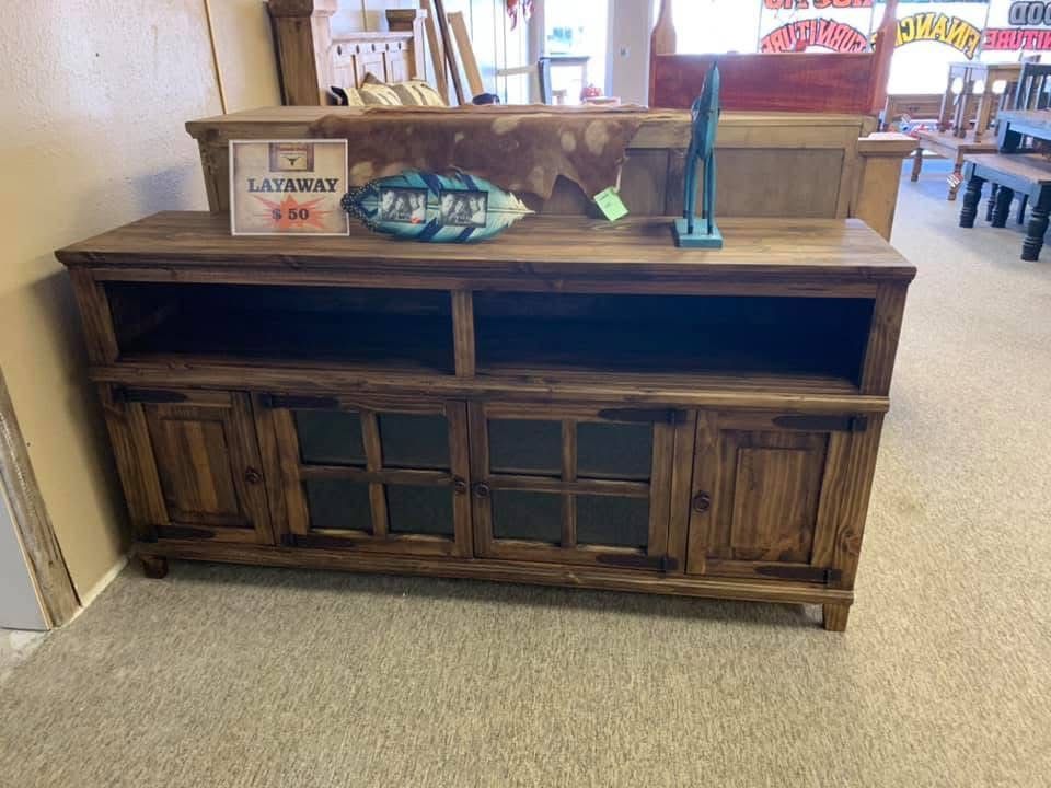 Wooden TV stand with cabinets, shelves, and decorative items in a store.