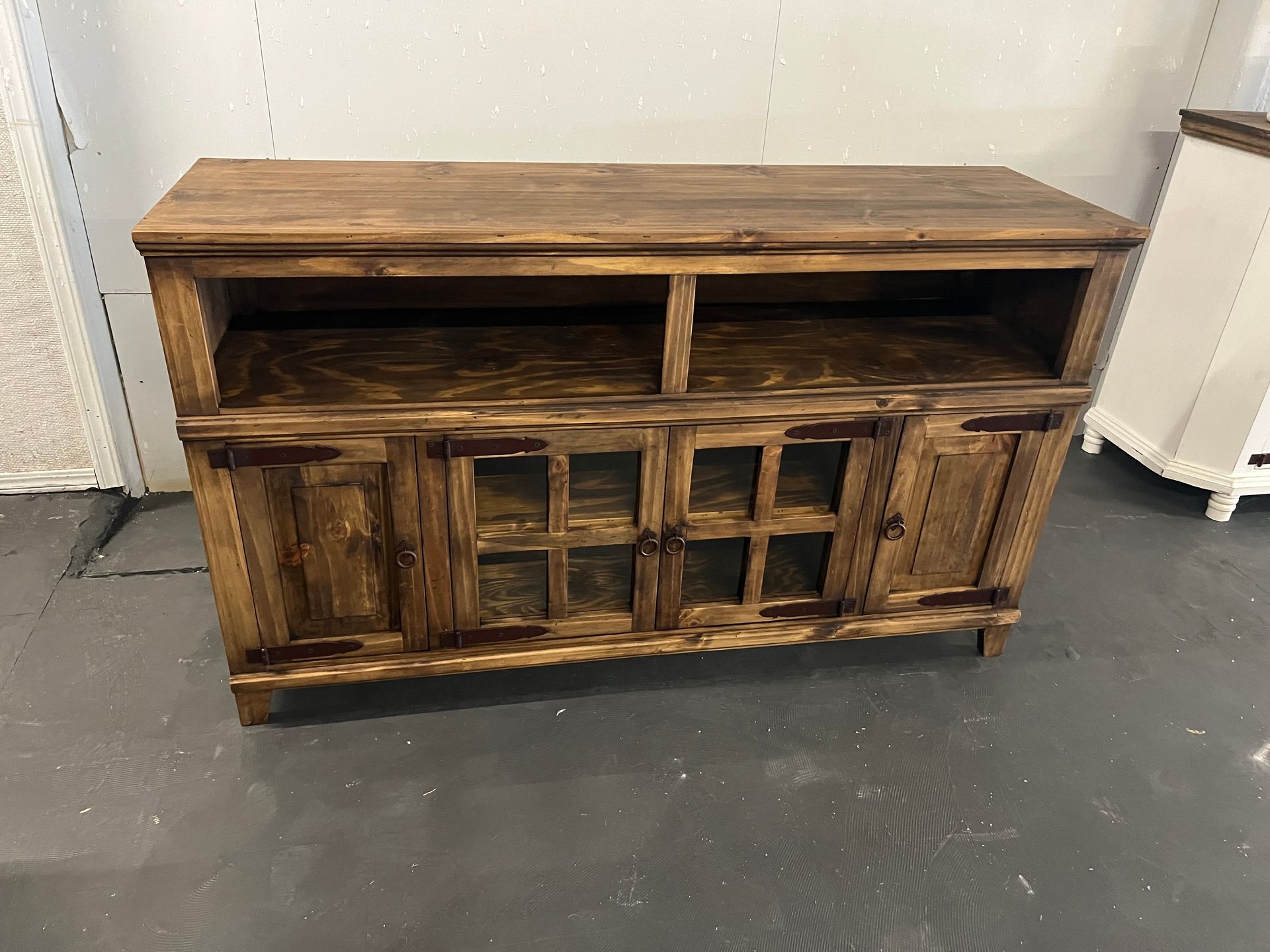 A TV on a rustic wooden stand displays a show. A couch and a cabinet are nearby.