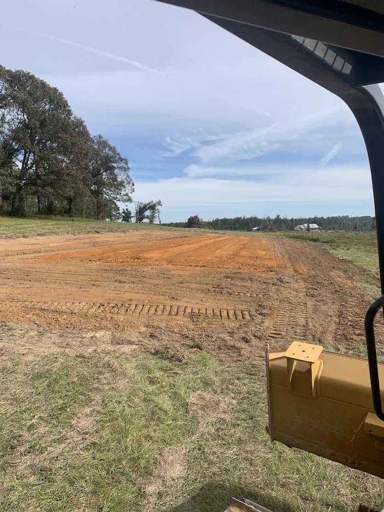 A tractor is driving down a dirt road in a field.