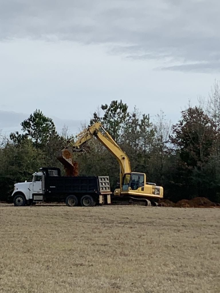 A yellow excavator is loading dirt into a dump truck.