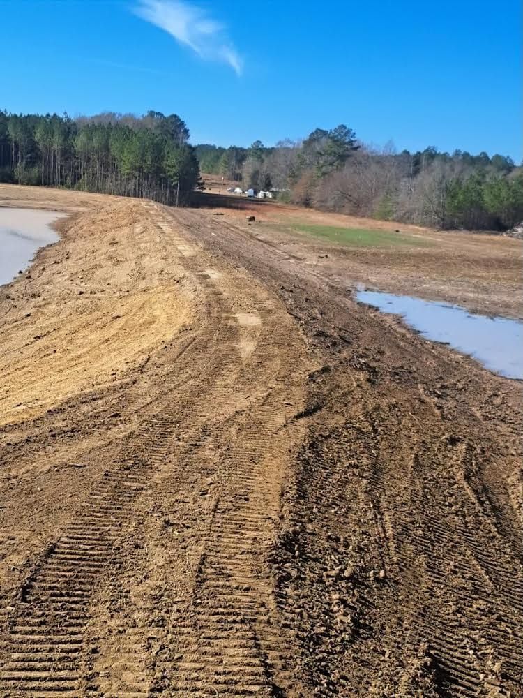 A dirt road leading to a body of water with trees in the background