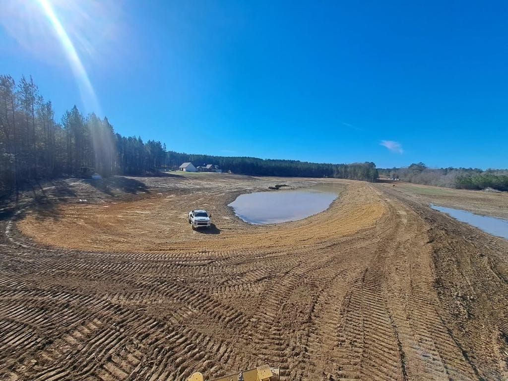 There is a small pond in the middle of a dirt field.