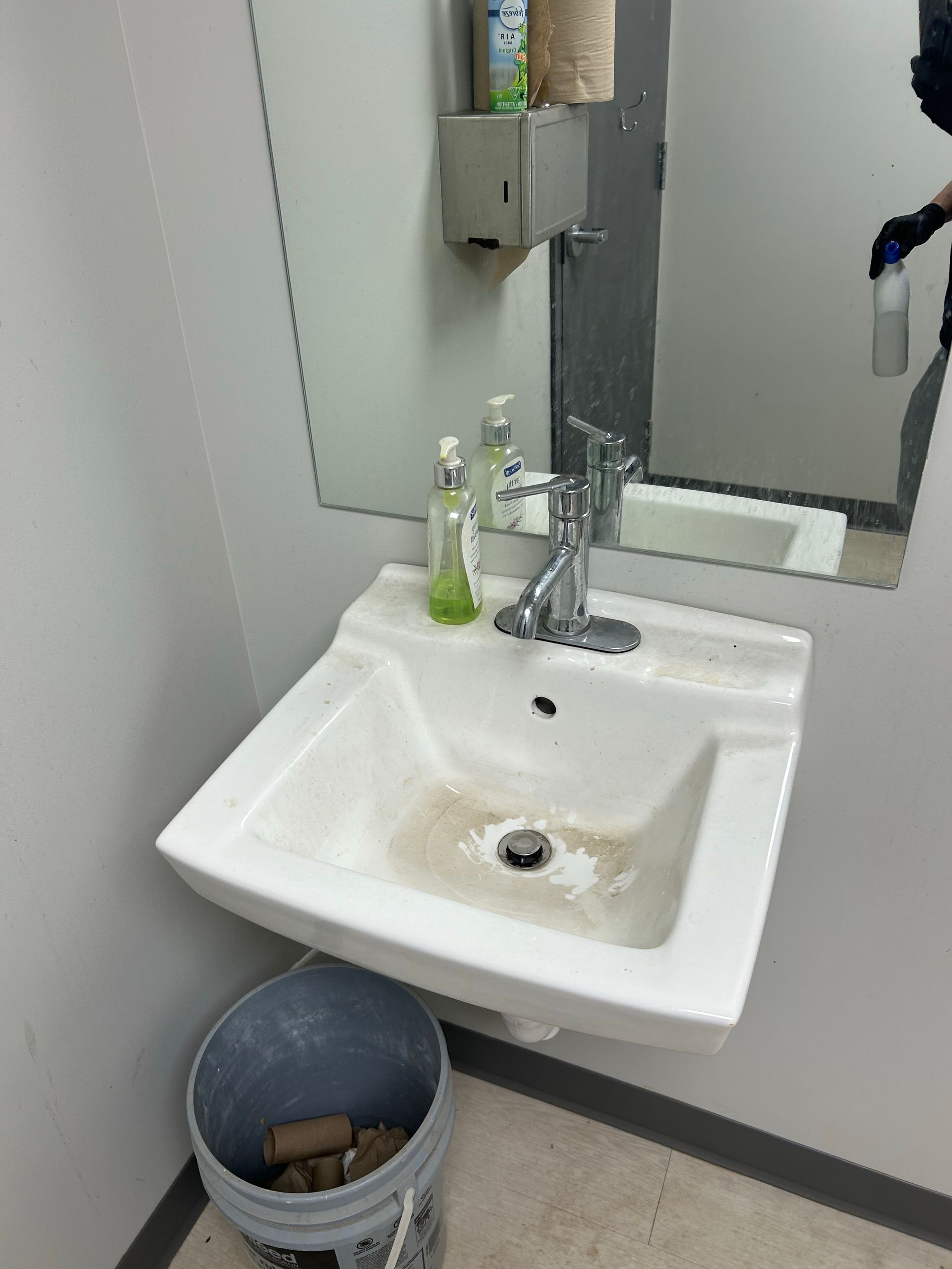 A bathroom sink with a bucket next to it