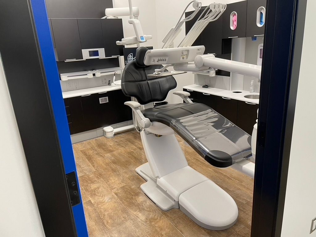 A dental office with a dental chair and a blue door.
