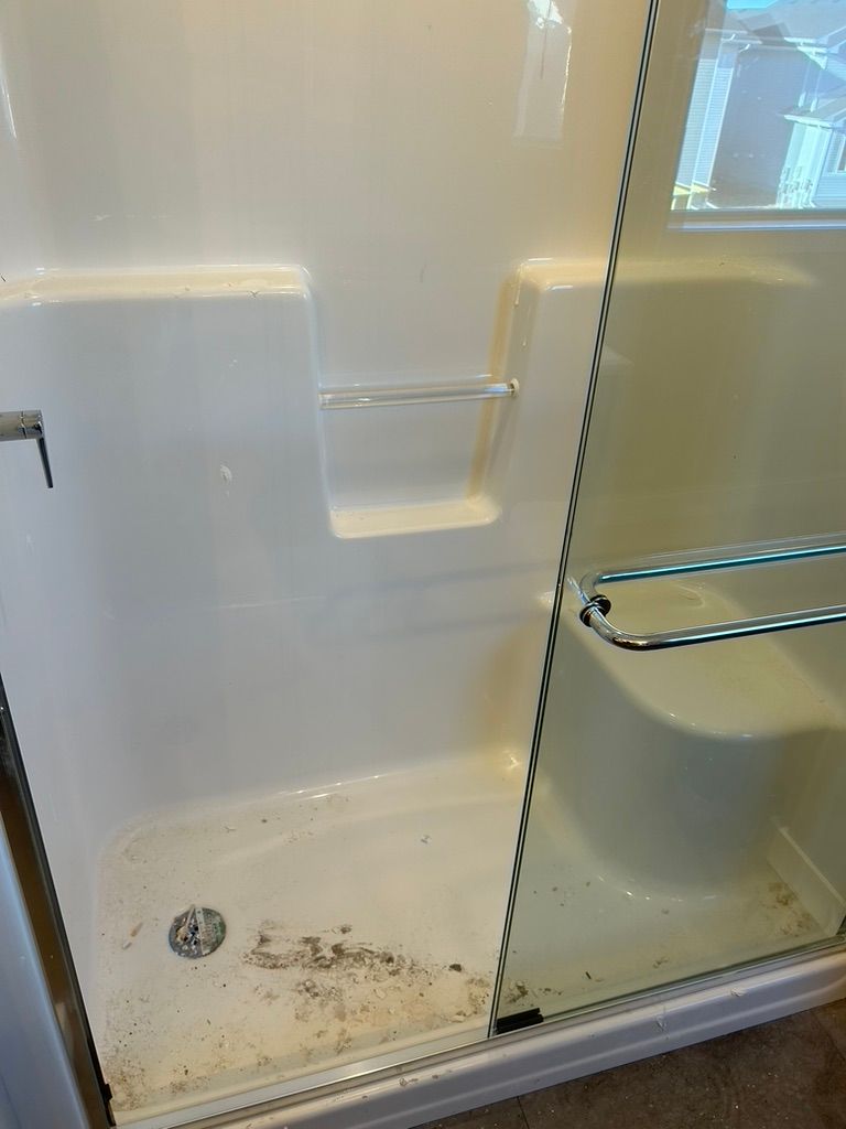 A dirty shower stall with a glass door in a bathroom.