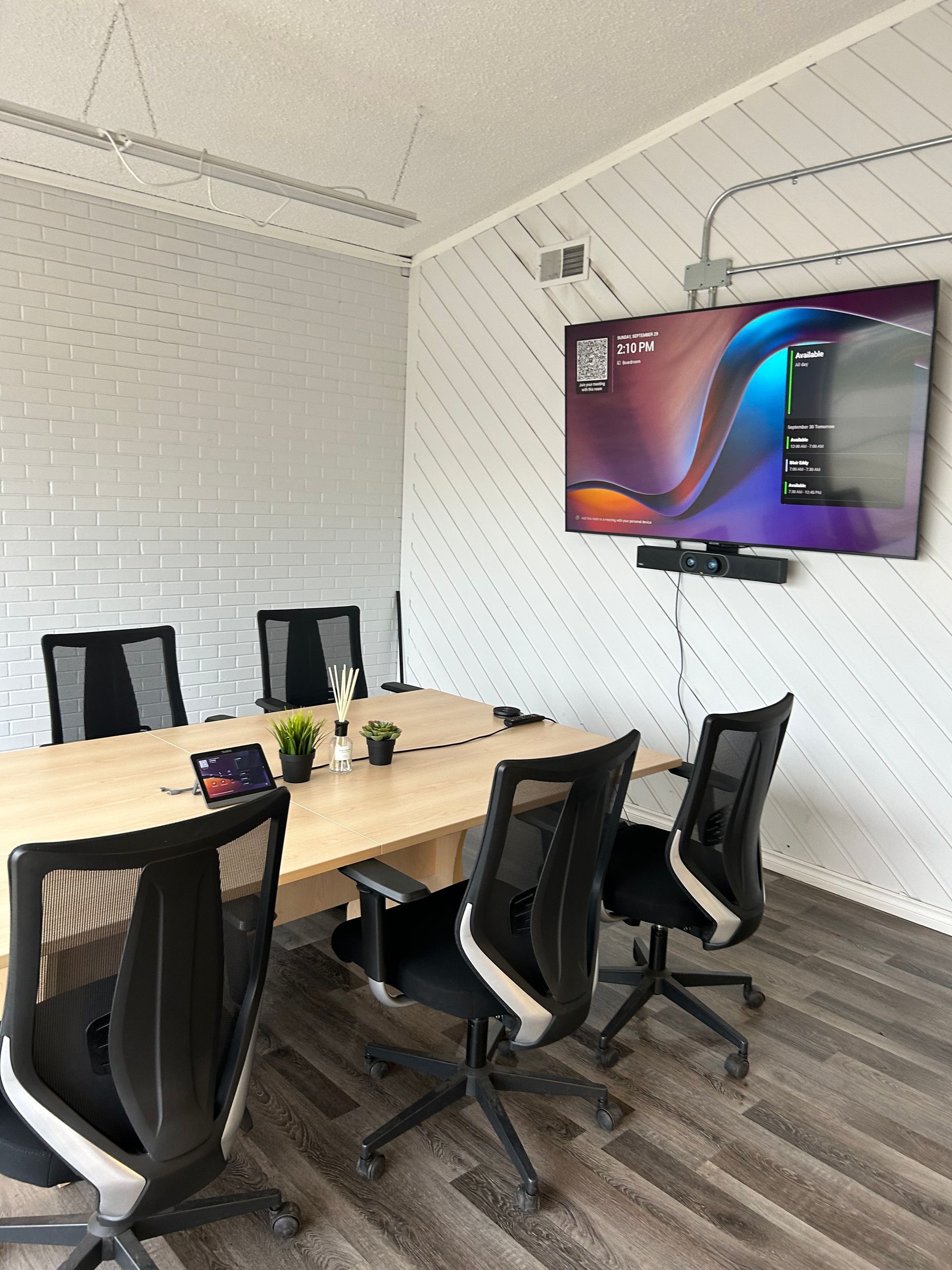 A conference room with a table and chairs and a flat screen tv
