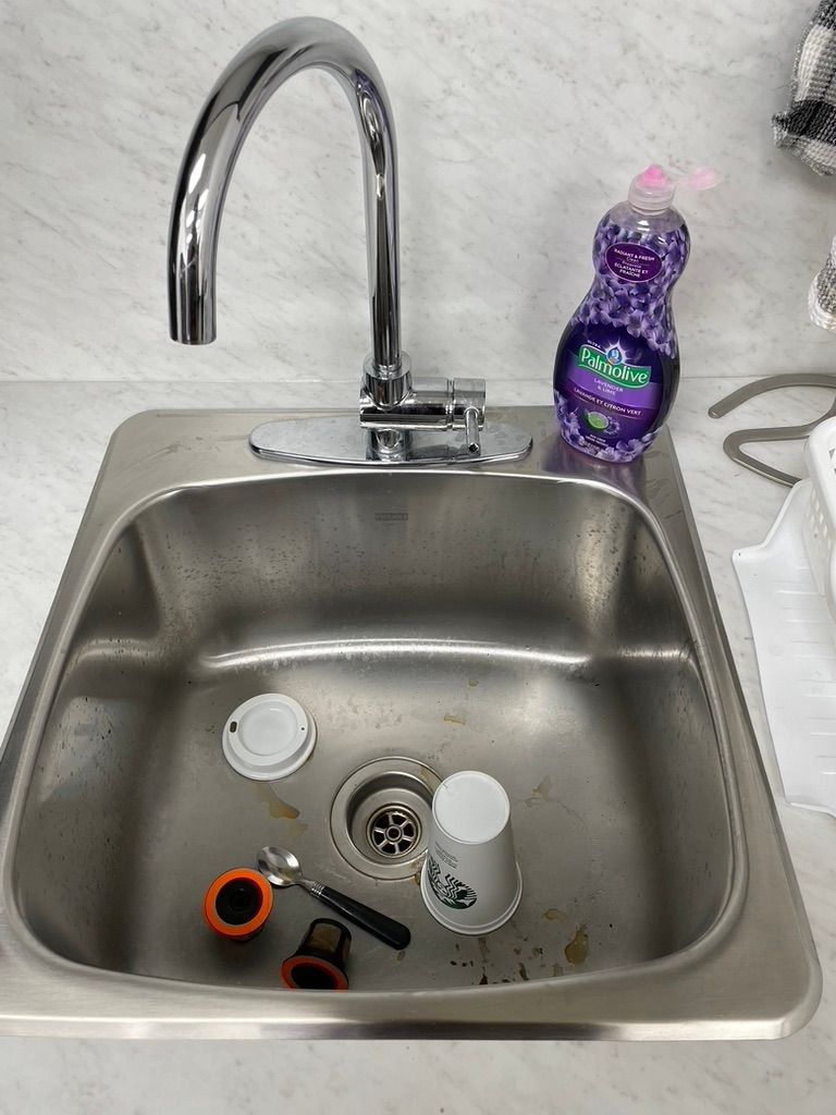 A stainless steel sink with a bottle of dish soap next to it.