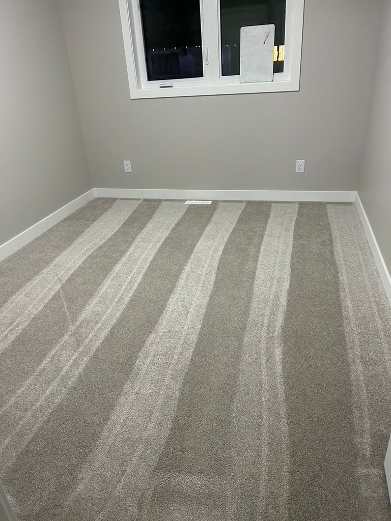 A bedroom with a striped carpet and a window.