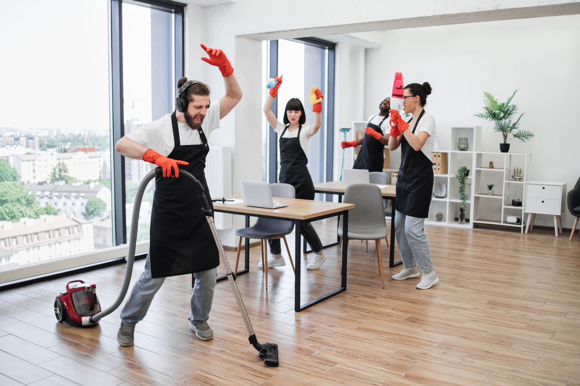 A group of people are cleaning an office with a vacuum cleaner.