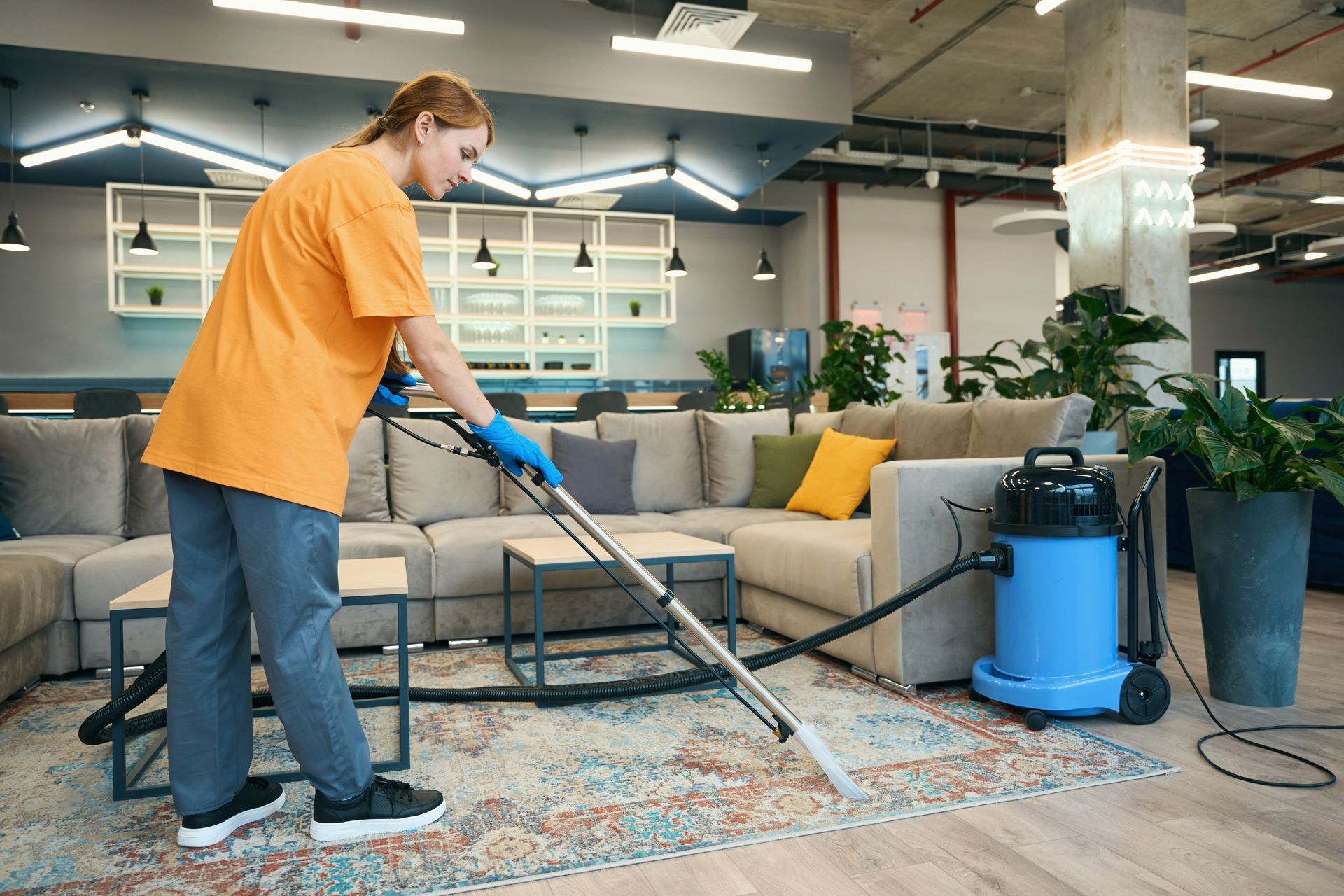 A woman is cleaning a living room with a vacuum cleaner.