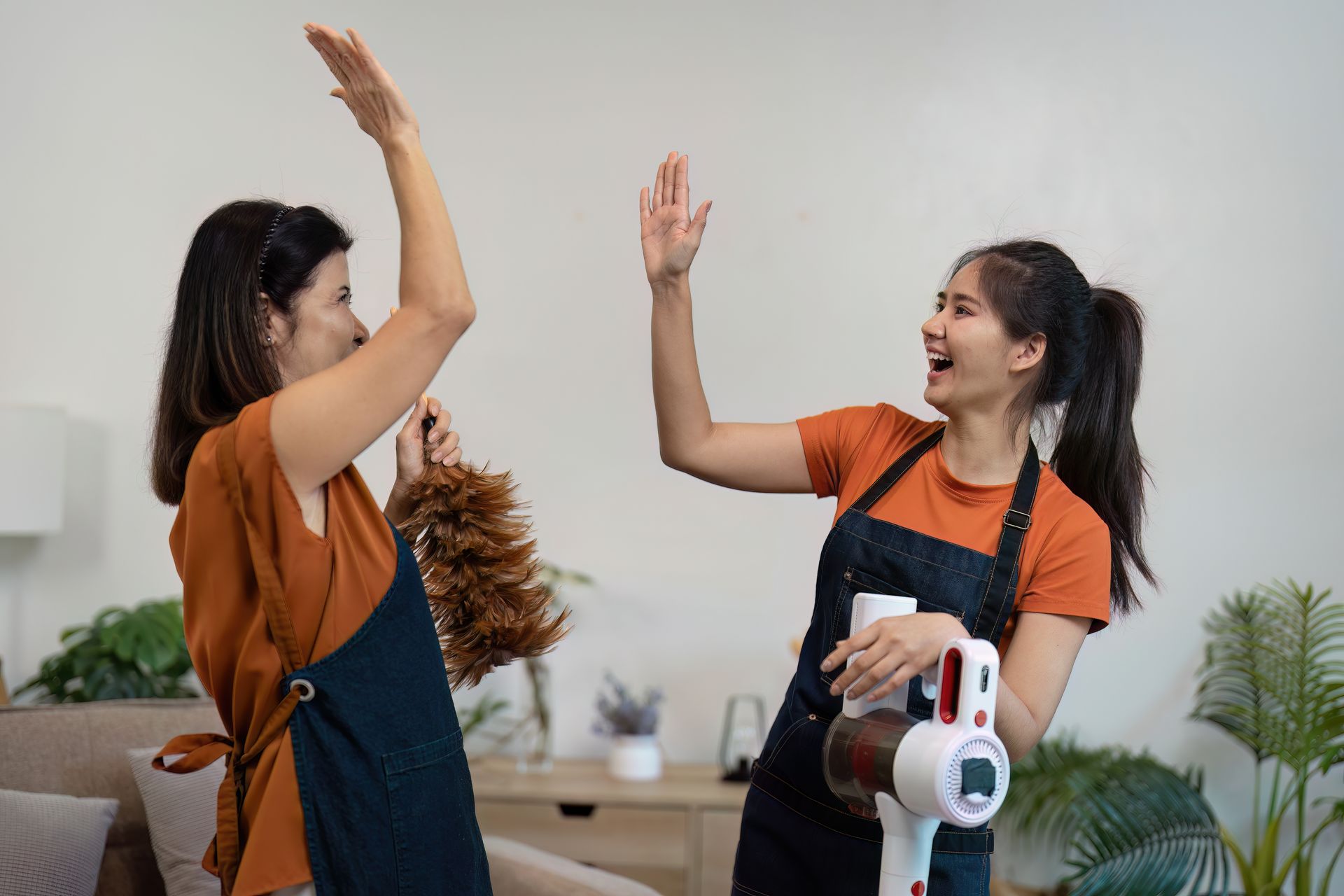 Two women are giving each other a high five while cleaning the house.