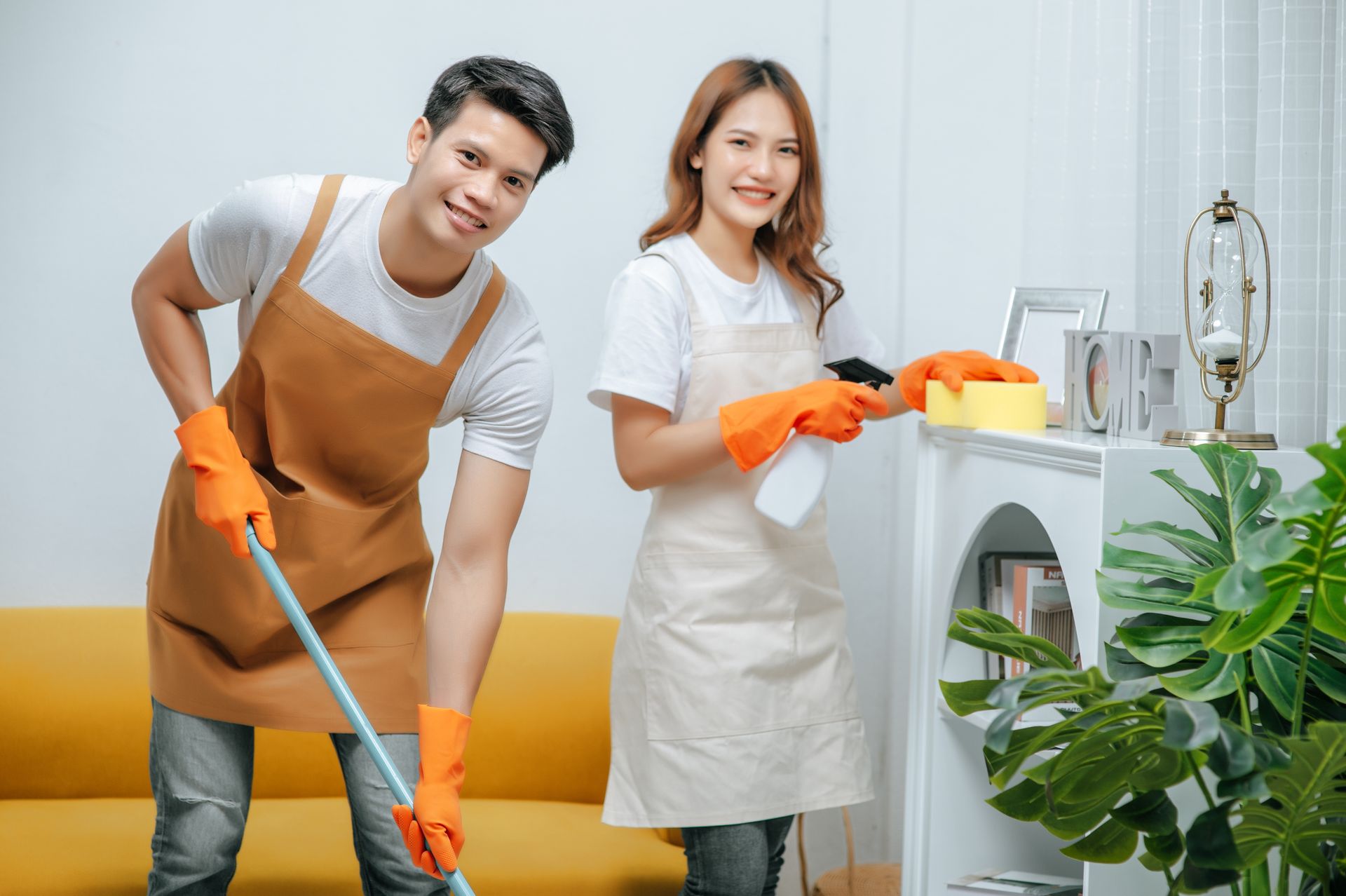 A man and a woman are cleaning a living room together.