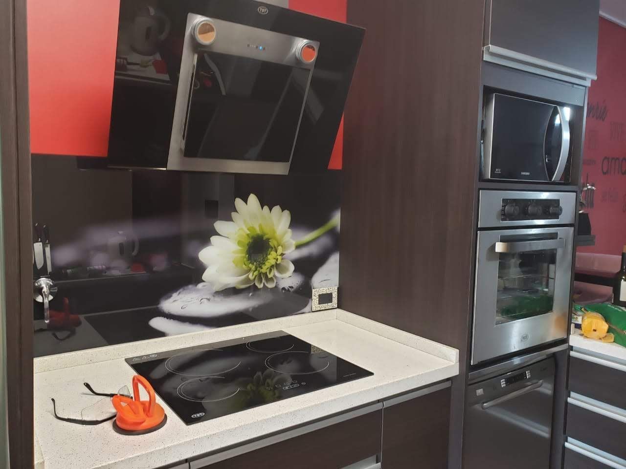 Cocina moderna con anafe de color negro, horno, microondas y gabinetes de color rojo y marrón.