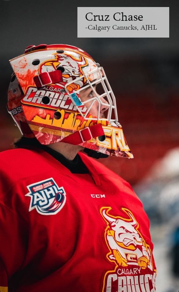 A Calgary Canucks hockey goalie wearing a red jersey and a custom-painted helmet with a city skyline design.