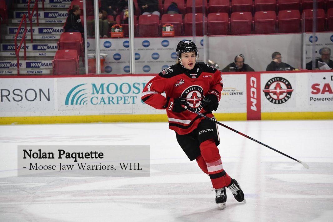 Nolan Paquette of the Moose Jaw Warriors skating on the ice in a red and black hockey uniform.