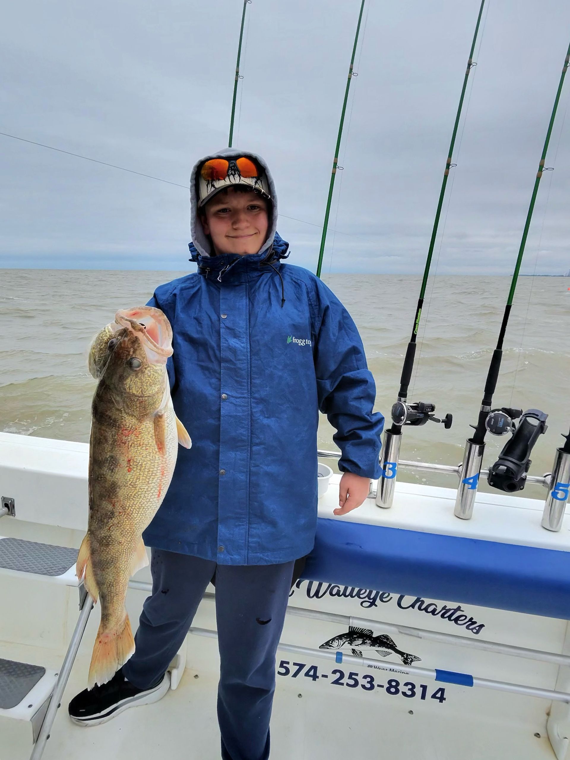A 13 year old boy holding Fish Ohio walleye caught on the Sir Walleye Charters boat with a Purple Demon color spoon in April of 2026.