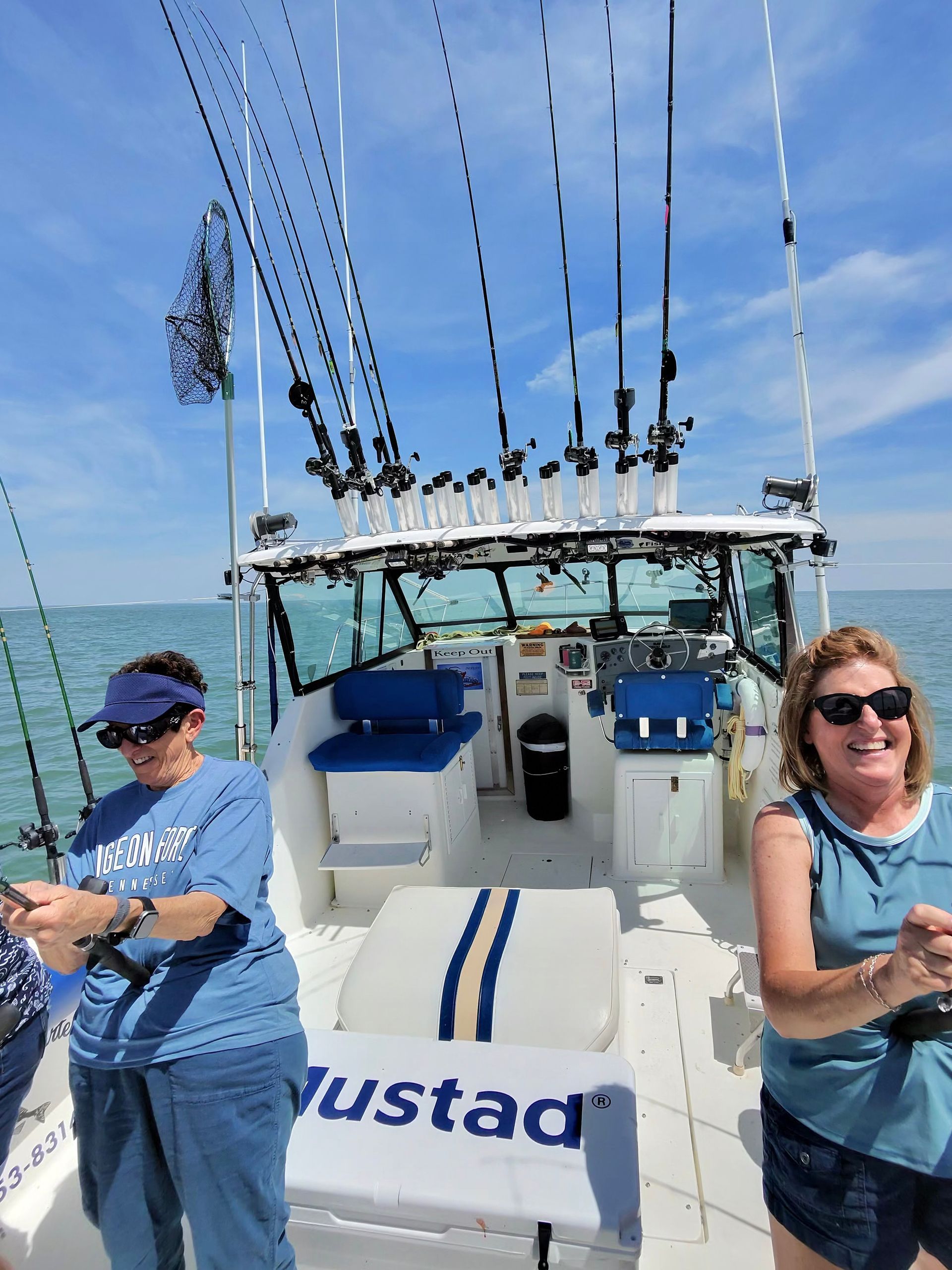 Two Women reeling in Lake Erie Walleye smiling on the Sir Walleye Charters Boat.