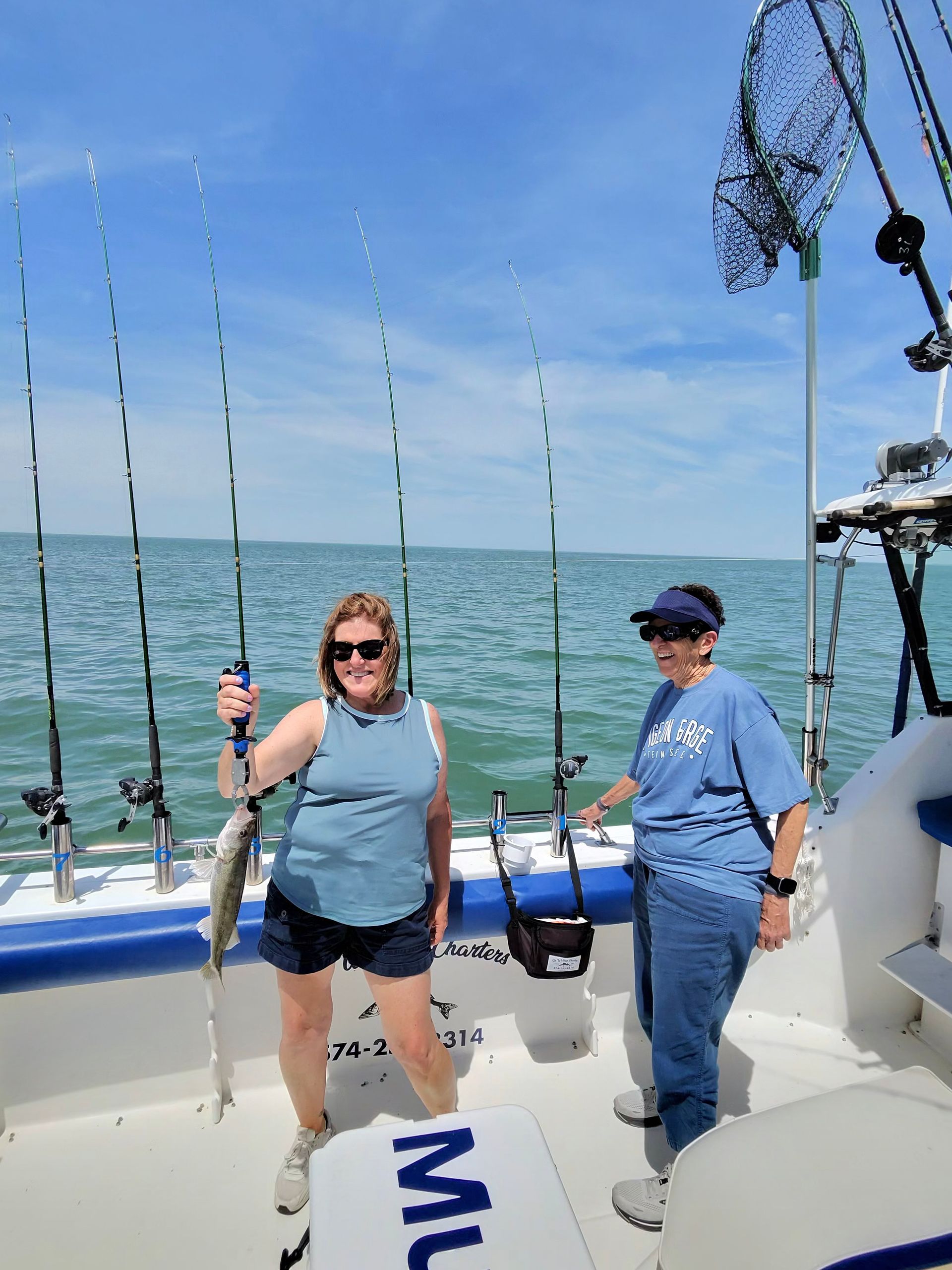 Women hold a Lake Erie walleye with Mustad fish grips.