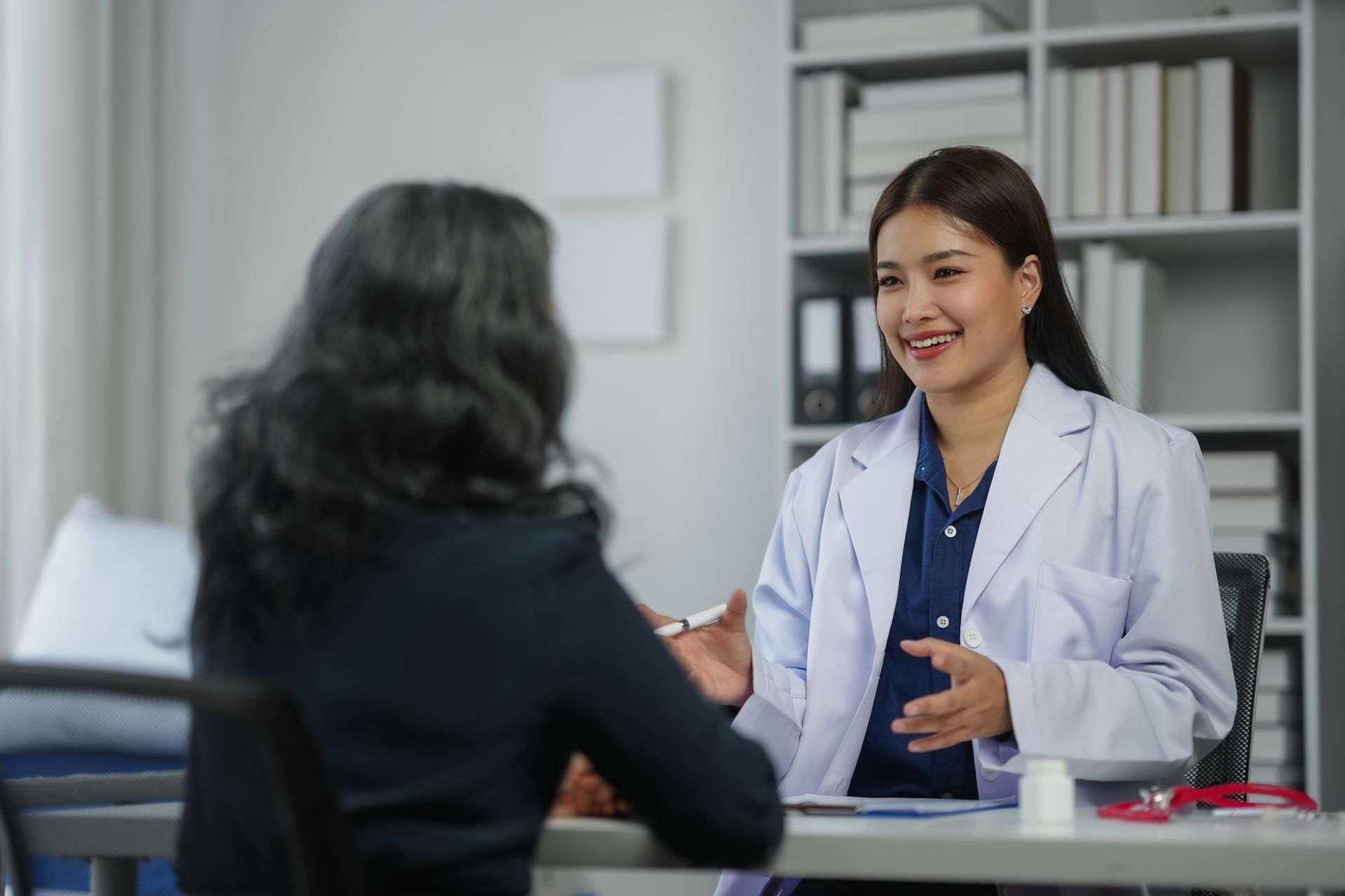 A doctor is talking to a patient who is sitting at a desk.