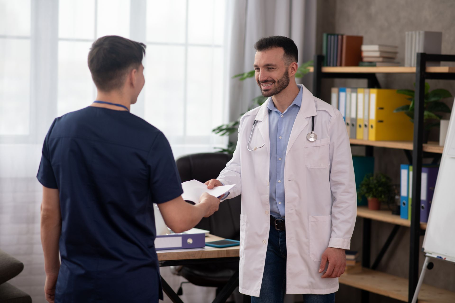 A doctor is shaking hands with a nurse in an office.