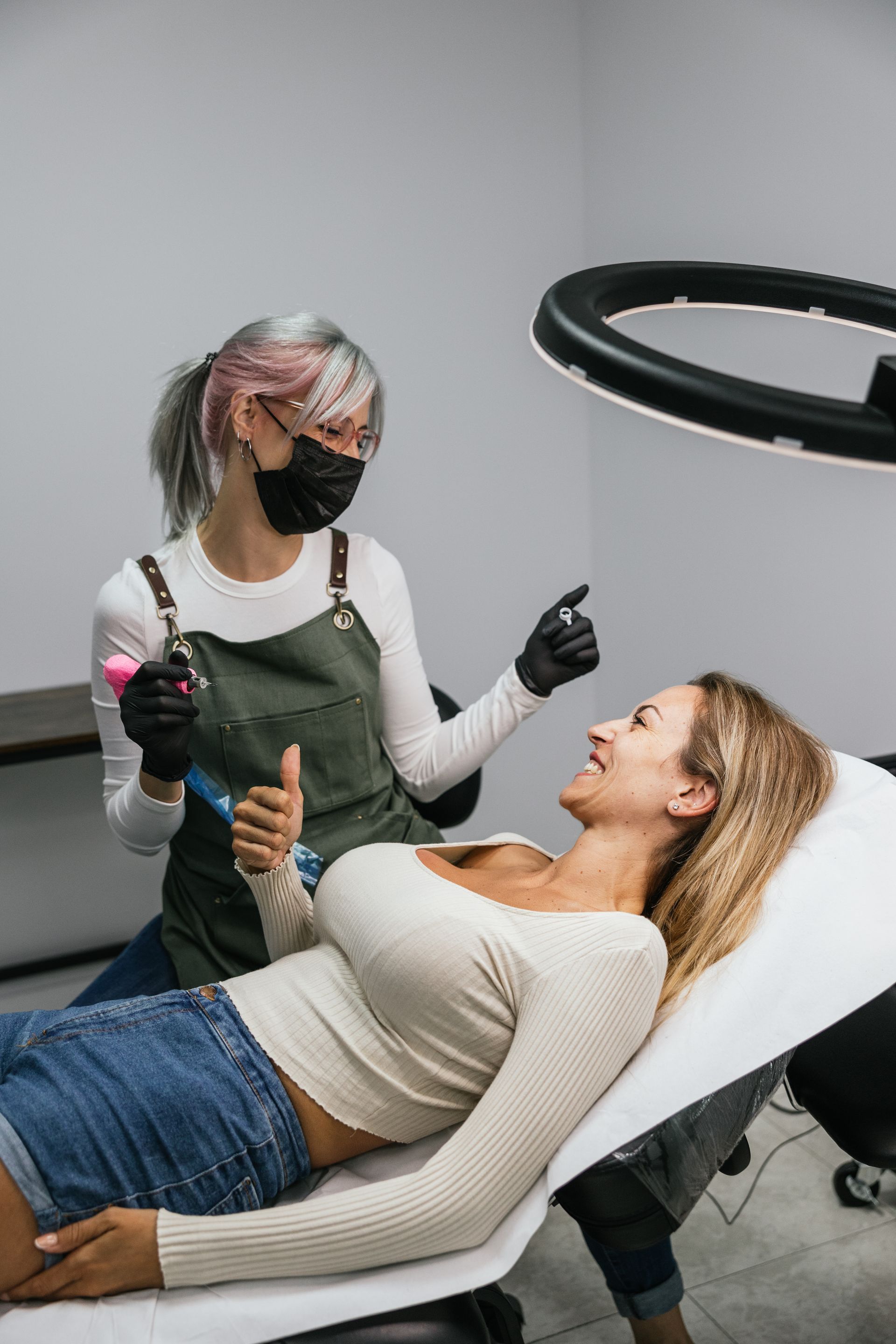A woman is laying on a bed getting a tattoo.