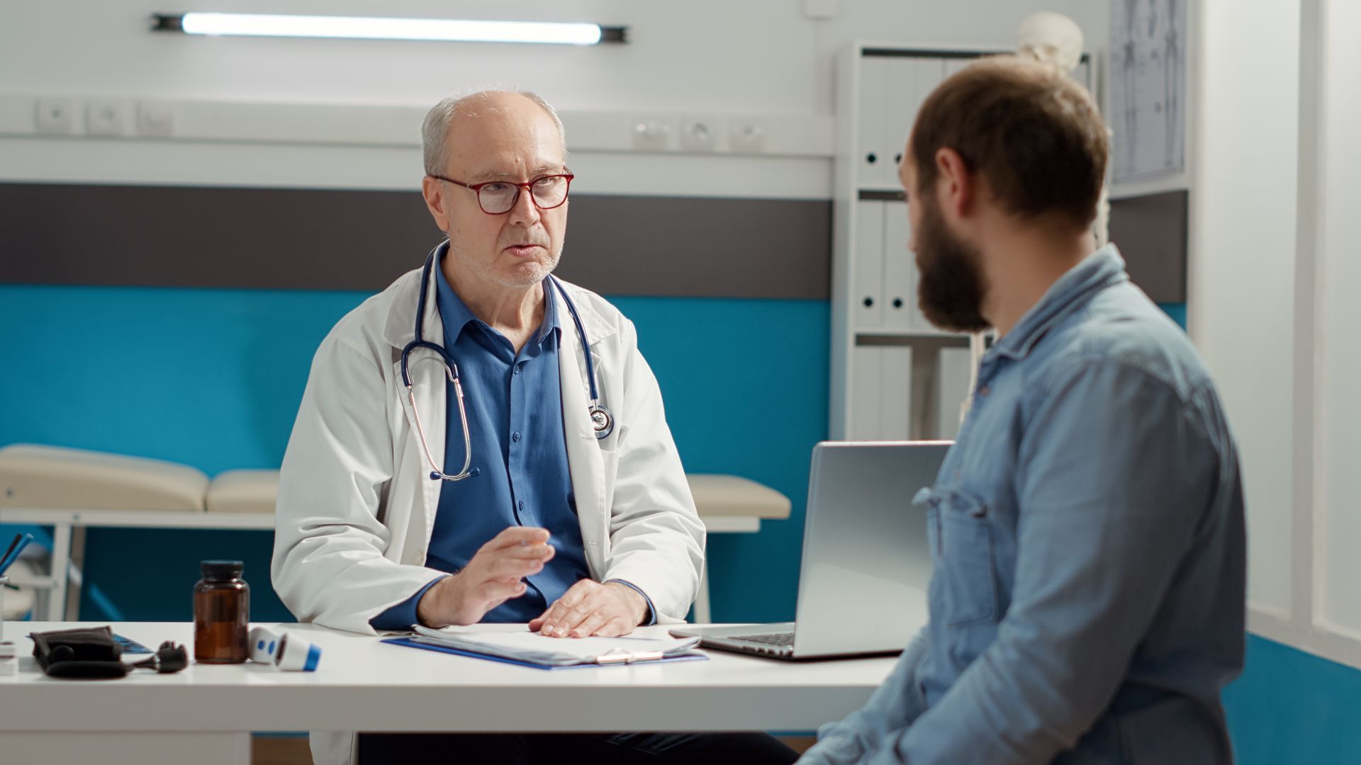 A doctor is sitting at a desk talking to a patient.