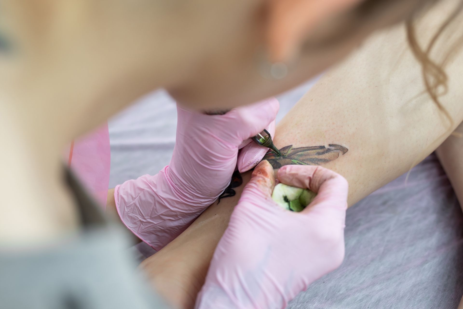 A woman is getting a tattoo on her arm.