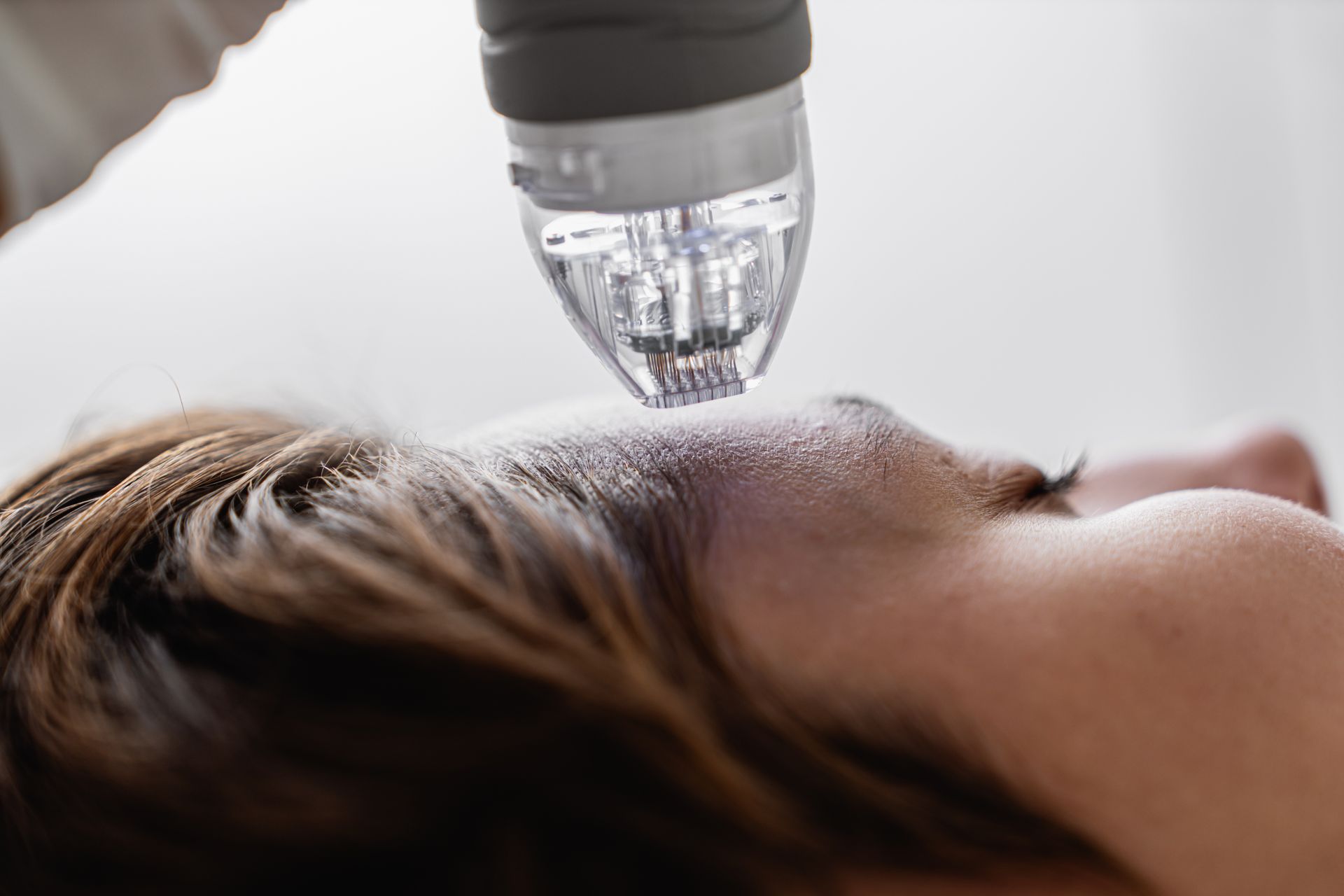 A woman is getting a facial treatment with a roller on her face.