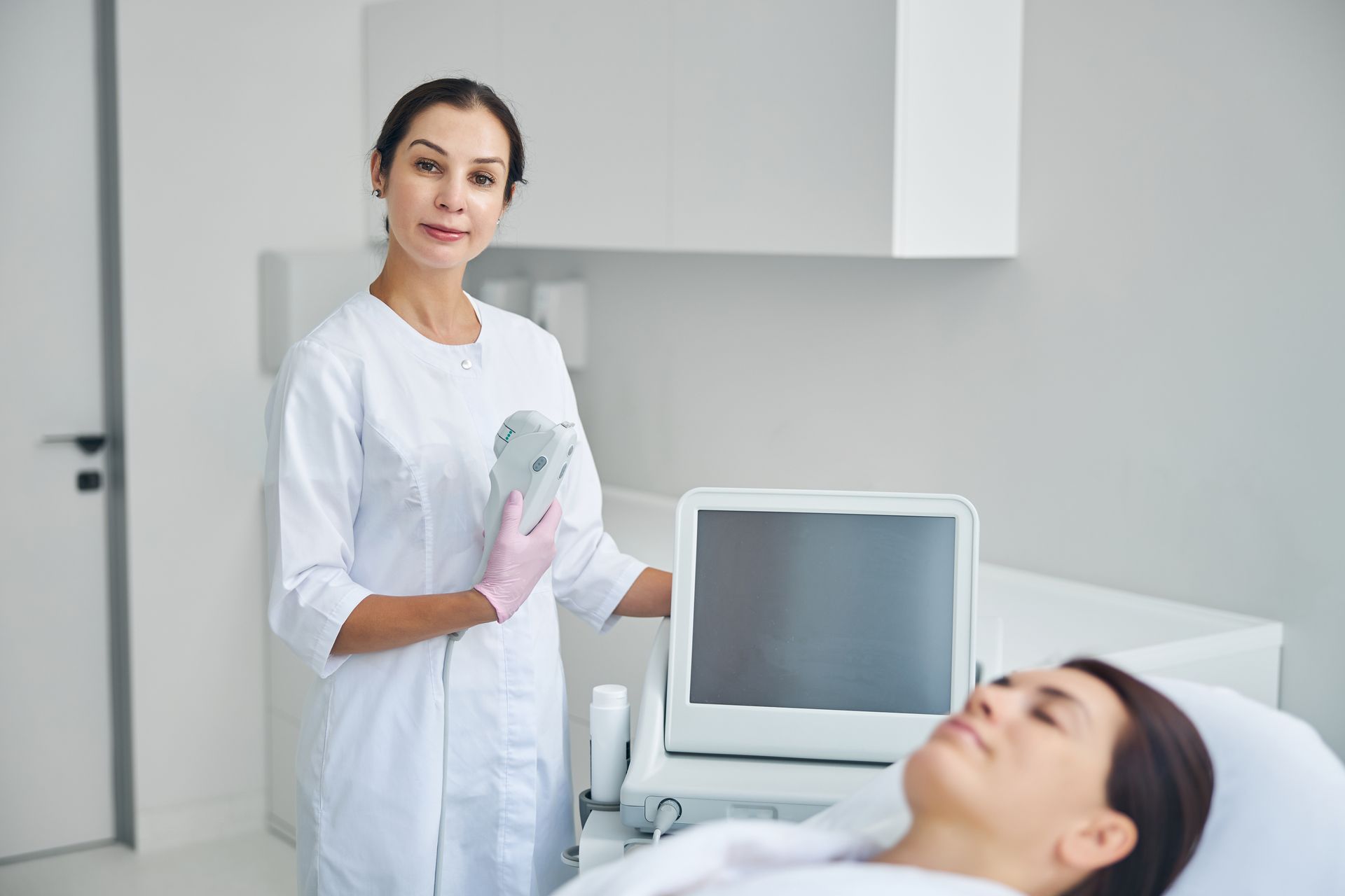 A female doctor is standing next to a woman laying in a hospital bed.