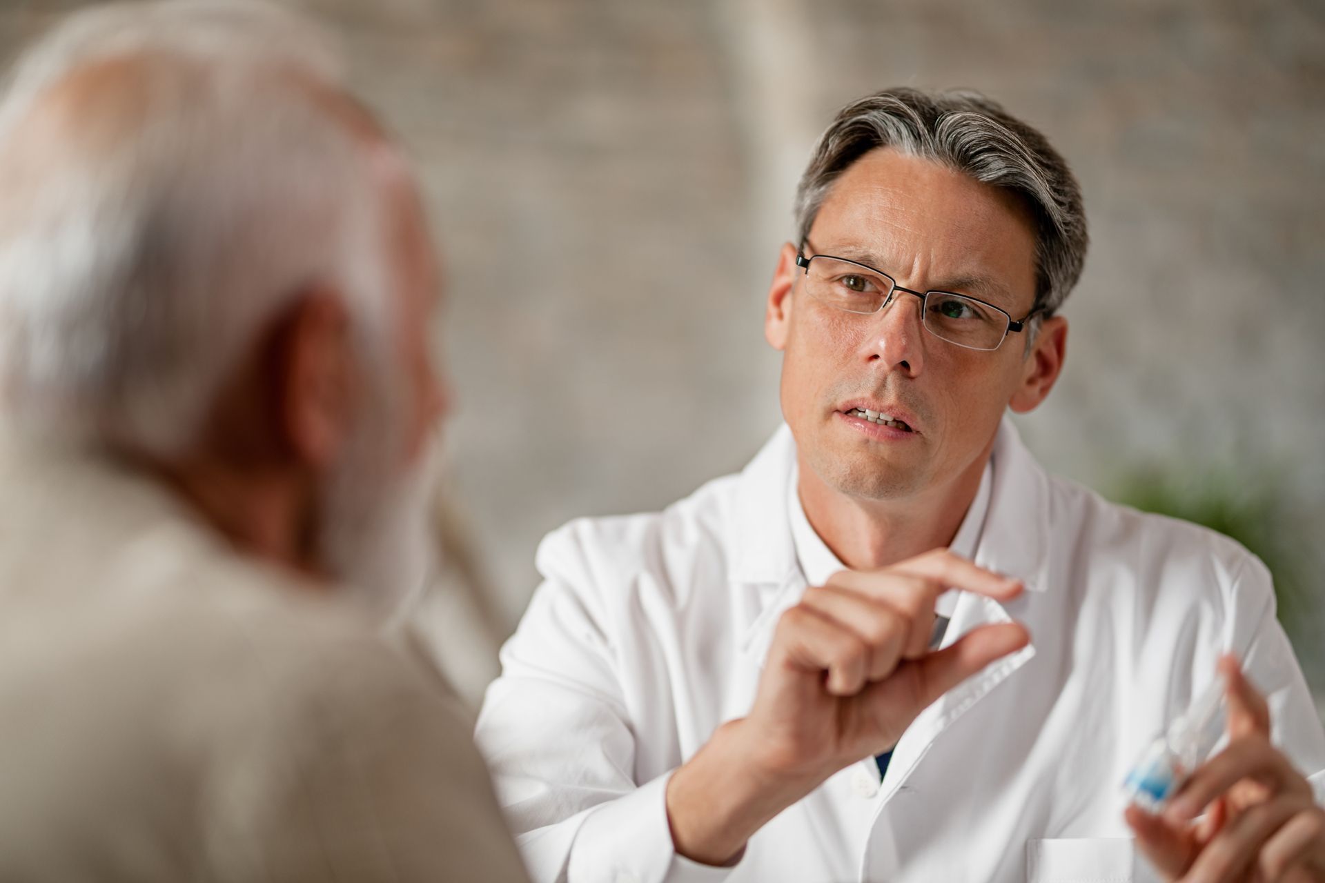 A doctor is talking to an older man while holding a syringe.