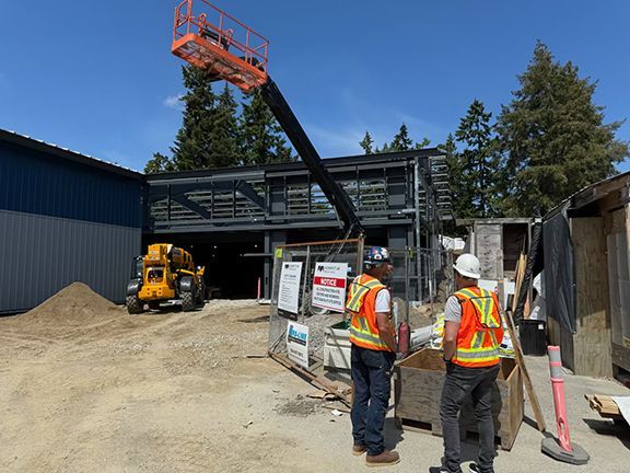 Engineers review blueprints in front of building's steel framing.