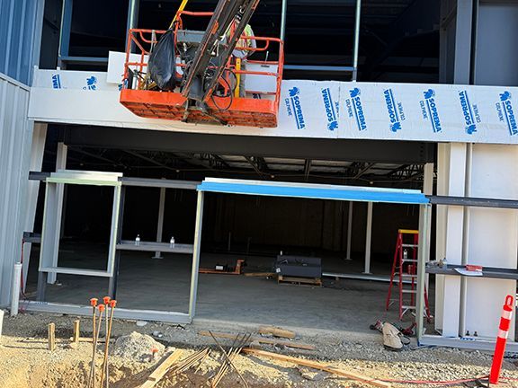 Men in crane add exterior wall panels to pre-engineered steel building project in Ganges, BC.