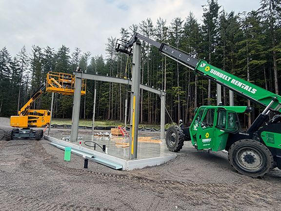 Primary steel framing gets added to foundation for building project.