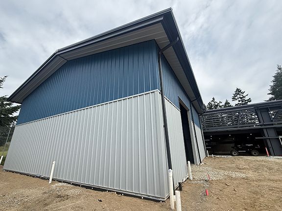 Side view of grey and blue metal wall panels at BC building construction site.