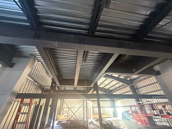 Closeup view of steel i-beam framing and metal flooring at PEMB job.