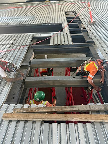 Skilled tradesmen installing metal floor system on steel building job in Salt Spring Island, BC.