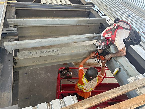 Tradesmen adding flooring panels to steel I-beams in Ganges, BC.
