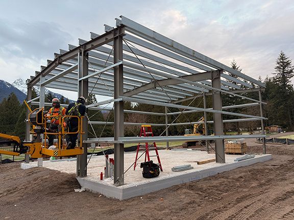 Two workers in a yellow lift install a steel frame building by Double Black Construction.