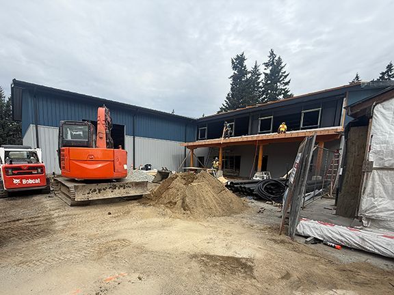 Equipment at work in front of metal building under construction in BC.