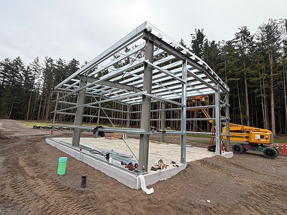A metal-framed building under construction on a concrete foundation.