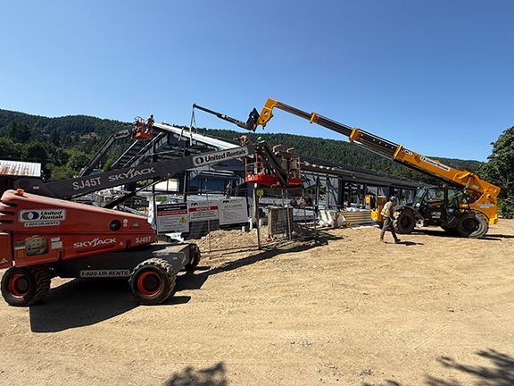 Metal beams being lowered into place at commercial building construction site.