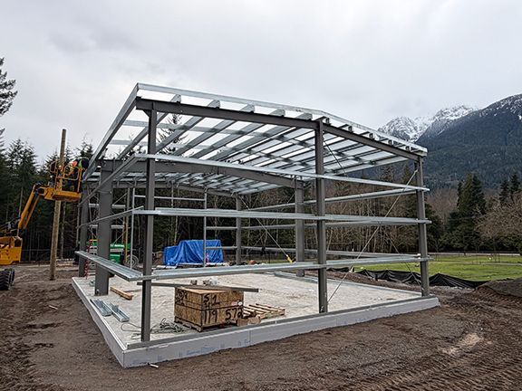 Cranes being used to lift steel roof frames into place.