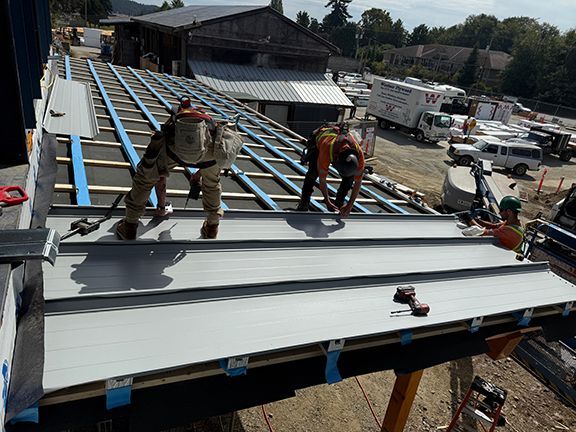 Workers bolting metal roof panels into place in B.C.