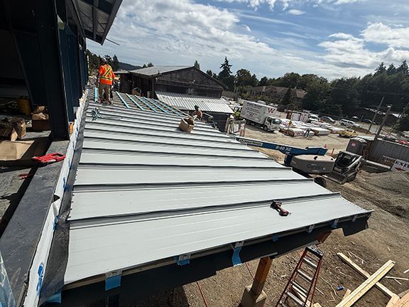 Roofing panels being added to building overhang in Ganges, BC.