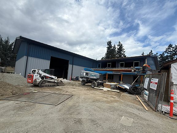 Various elevators and cranes sitting in front of metal building job site in Ganges, BC.