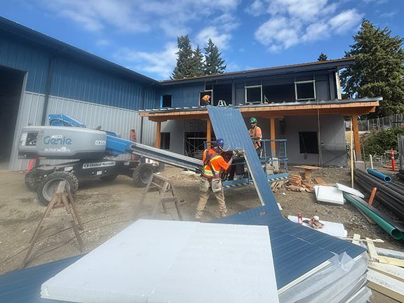 Skilled workers adding metal panels at building project at Ganges, Salt Spring Island.
